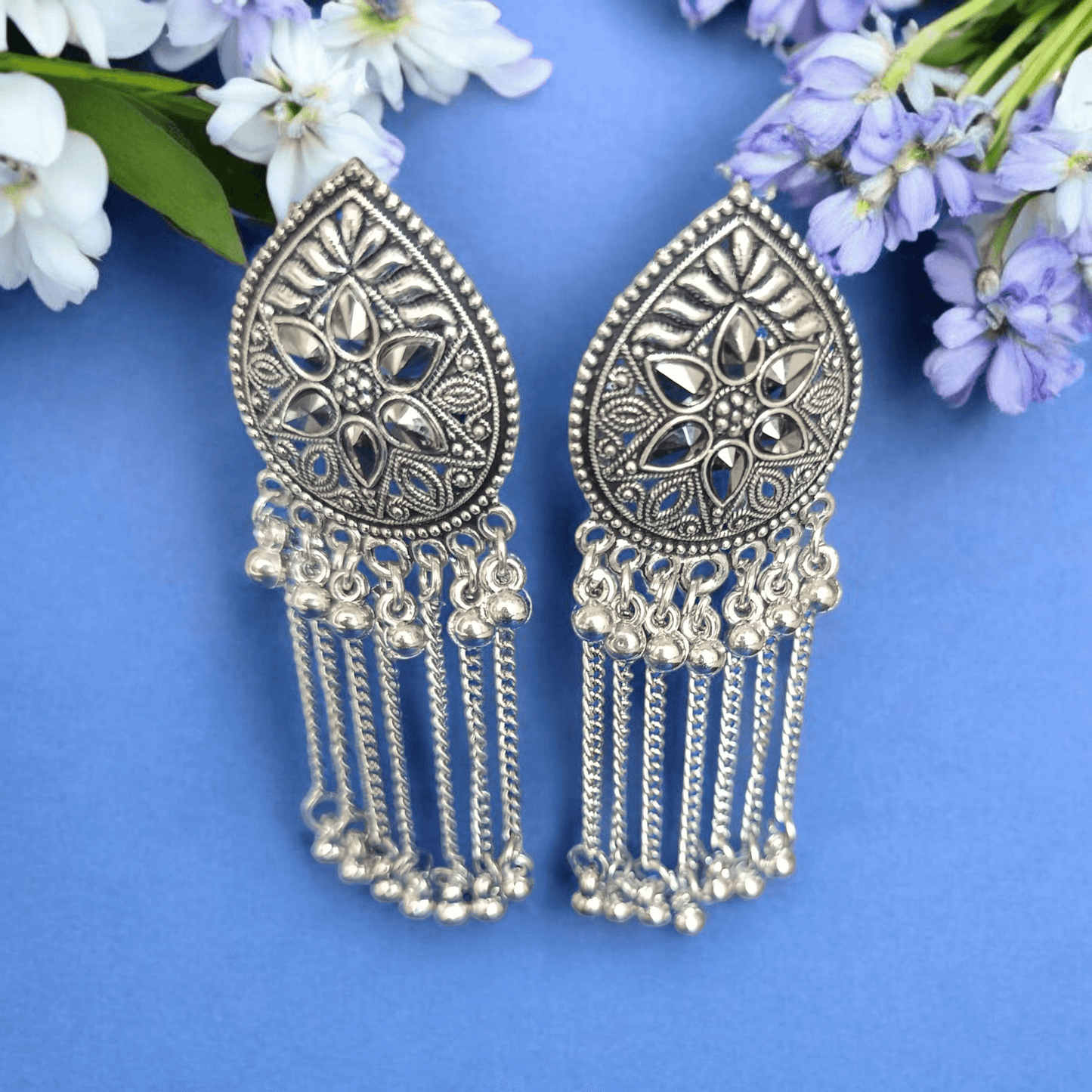 "Oxidized silver floral earrings with chain dangles on lavender background surrounded by flowers