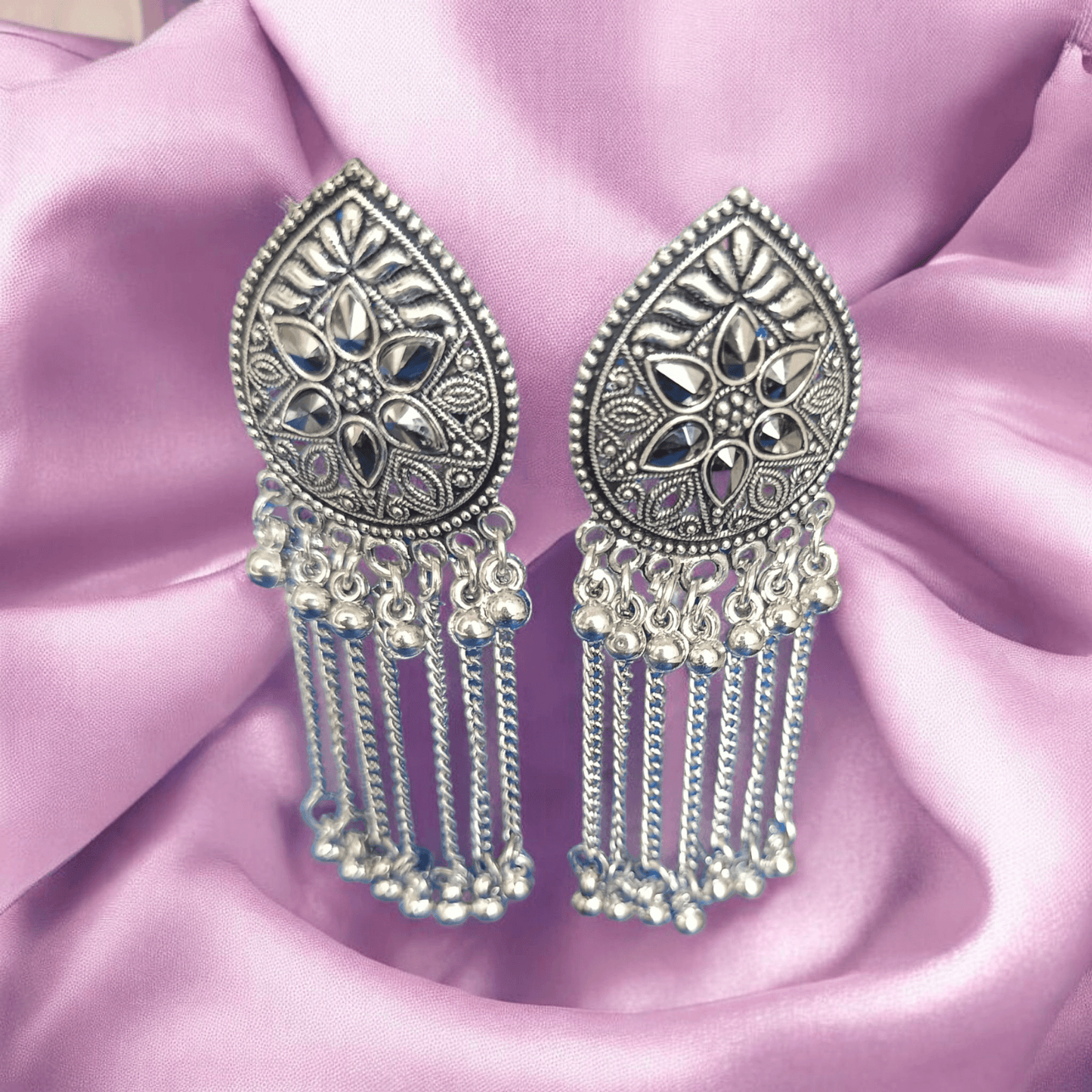 "Oxidized silver floral earrings with chain dangles on fabric background