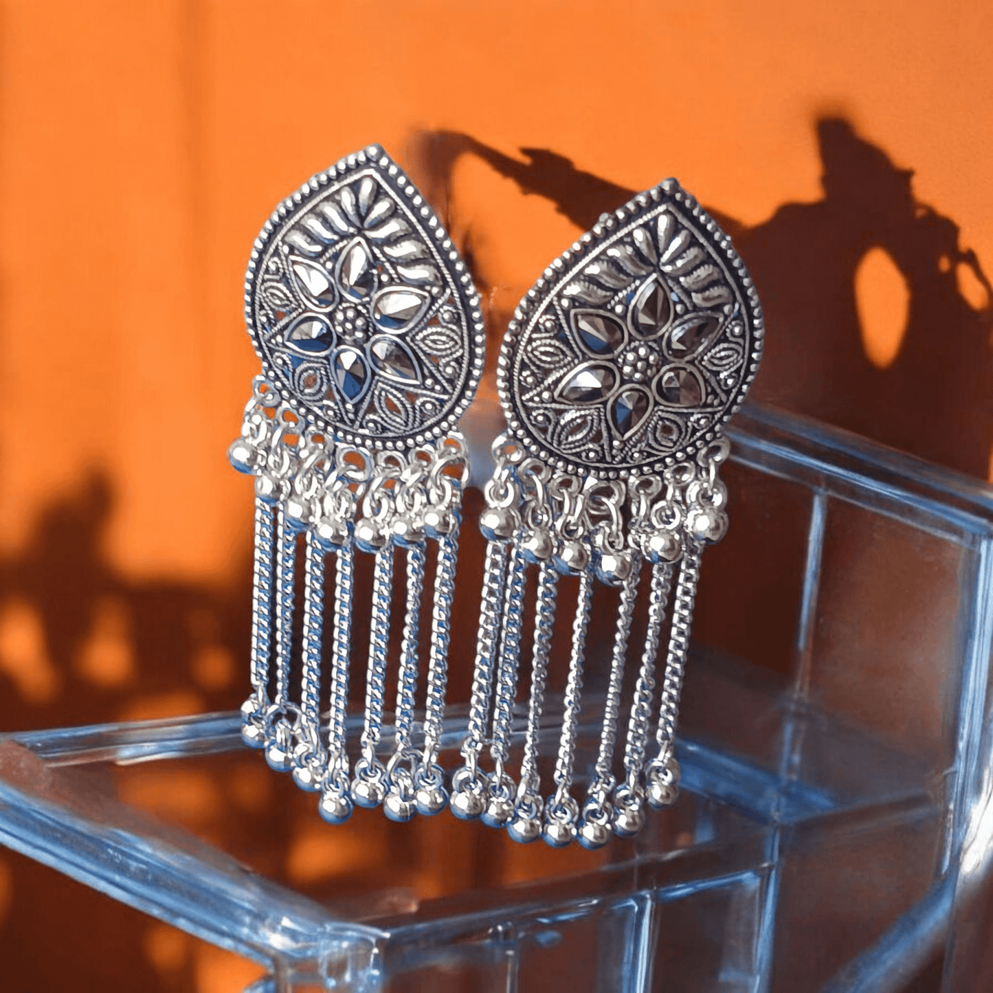"Oxidized silver floral earrings with chain dangles on mirror background