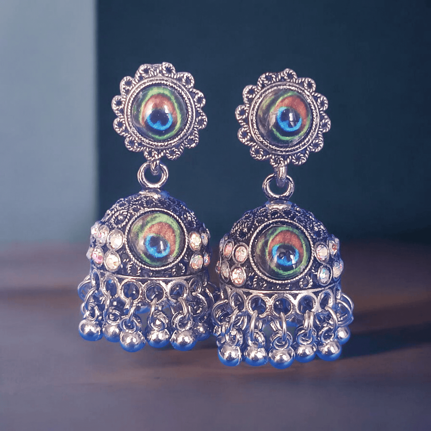 Peacock design oxidized silver jhumka earrings with rhinestones and minimalist background