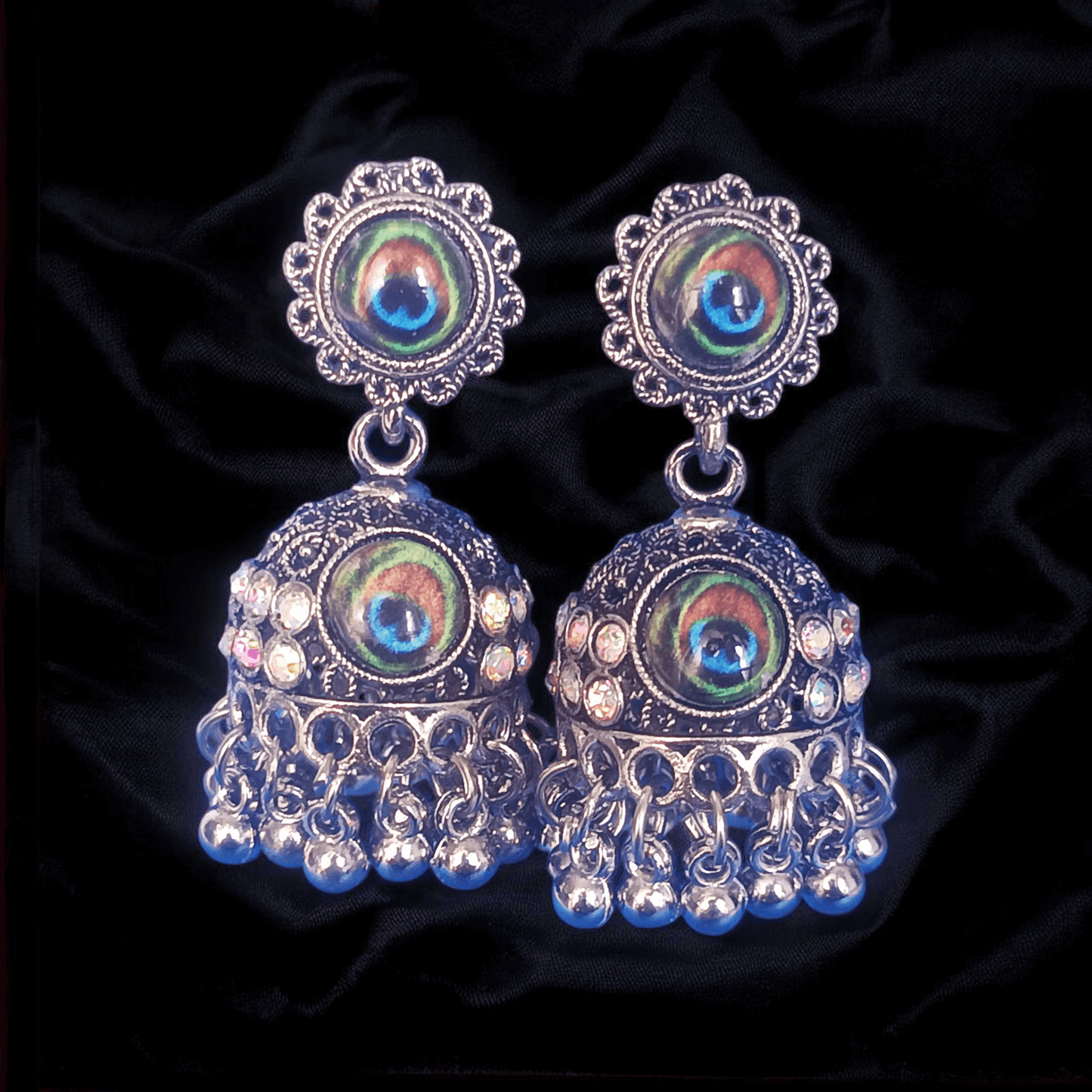 Peacock design oxidized silver jhumka earrings with rhinestones and black fabric background