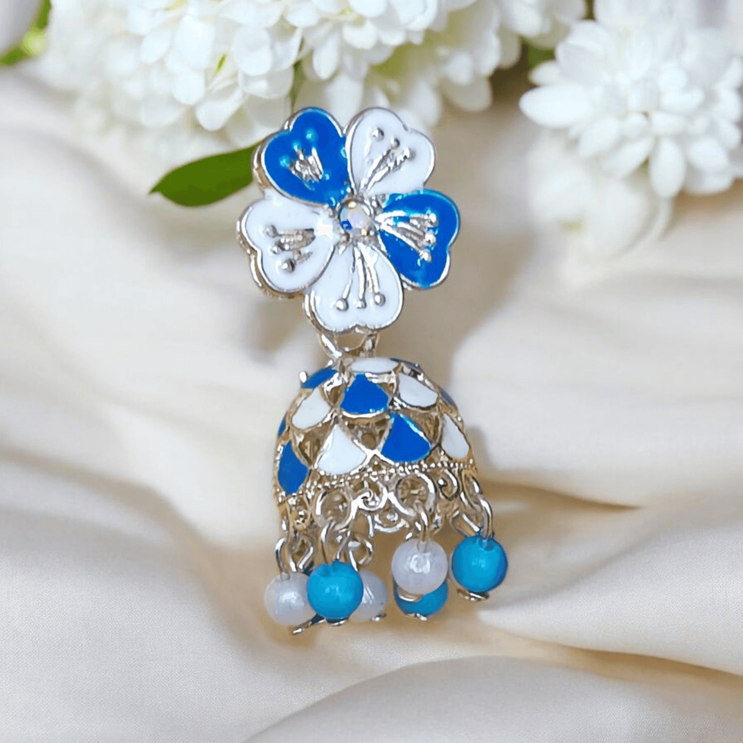 Selenesima blue floral oxidized jhumka earrings with pearls against white flowers background