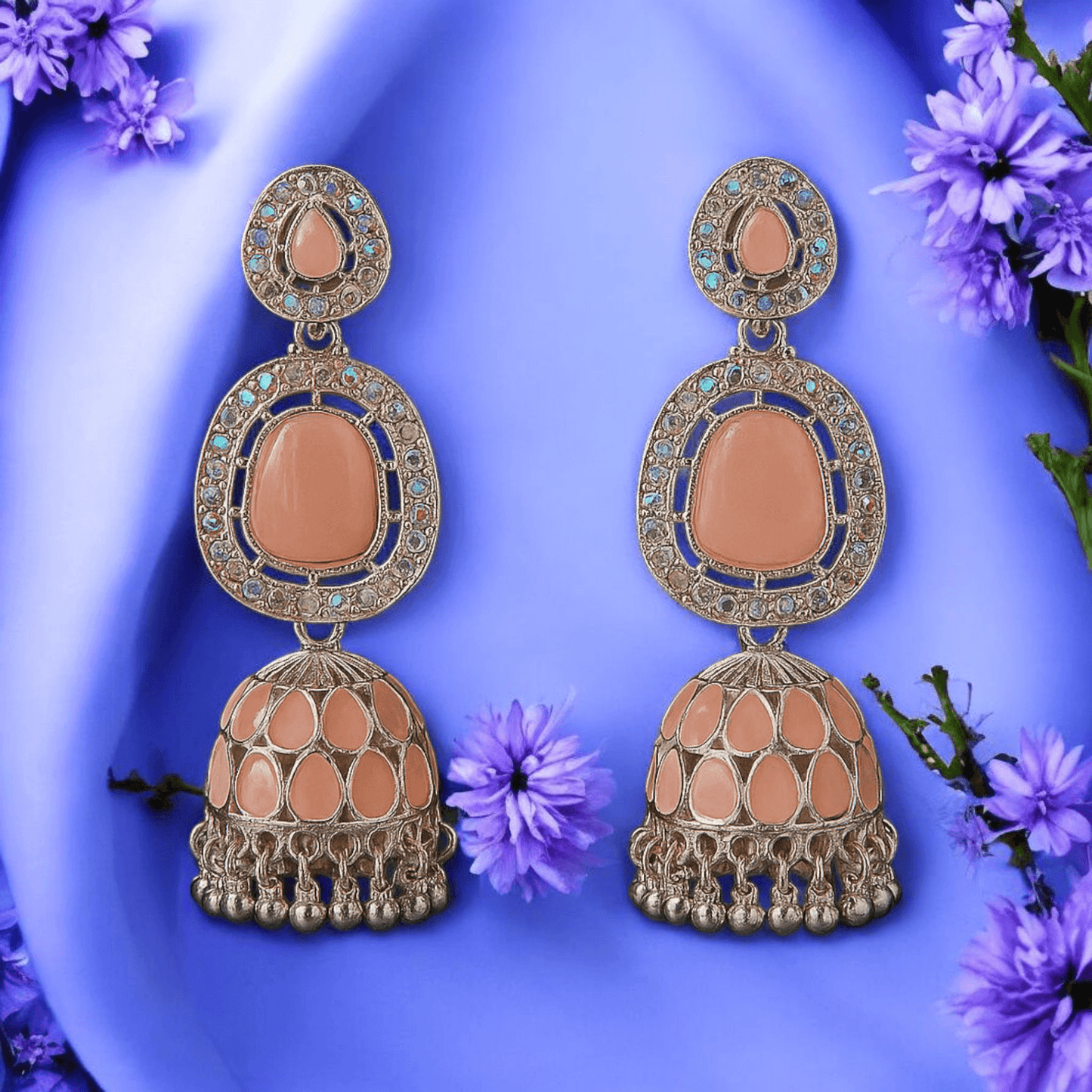Selenesima peach oxidized jhumka earrings with embellishments against lavender flowers background