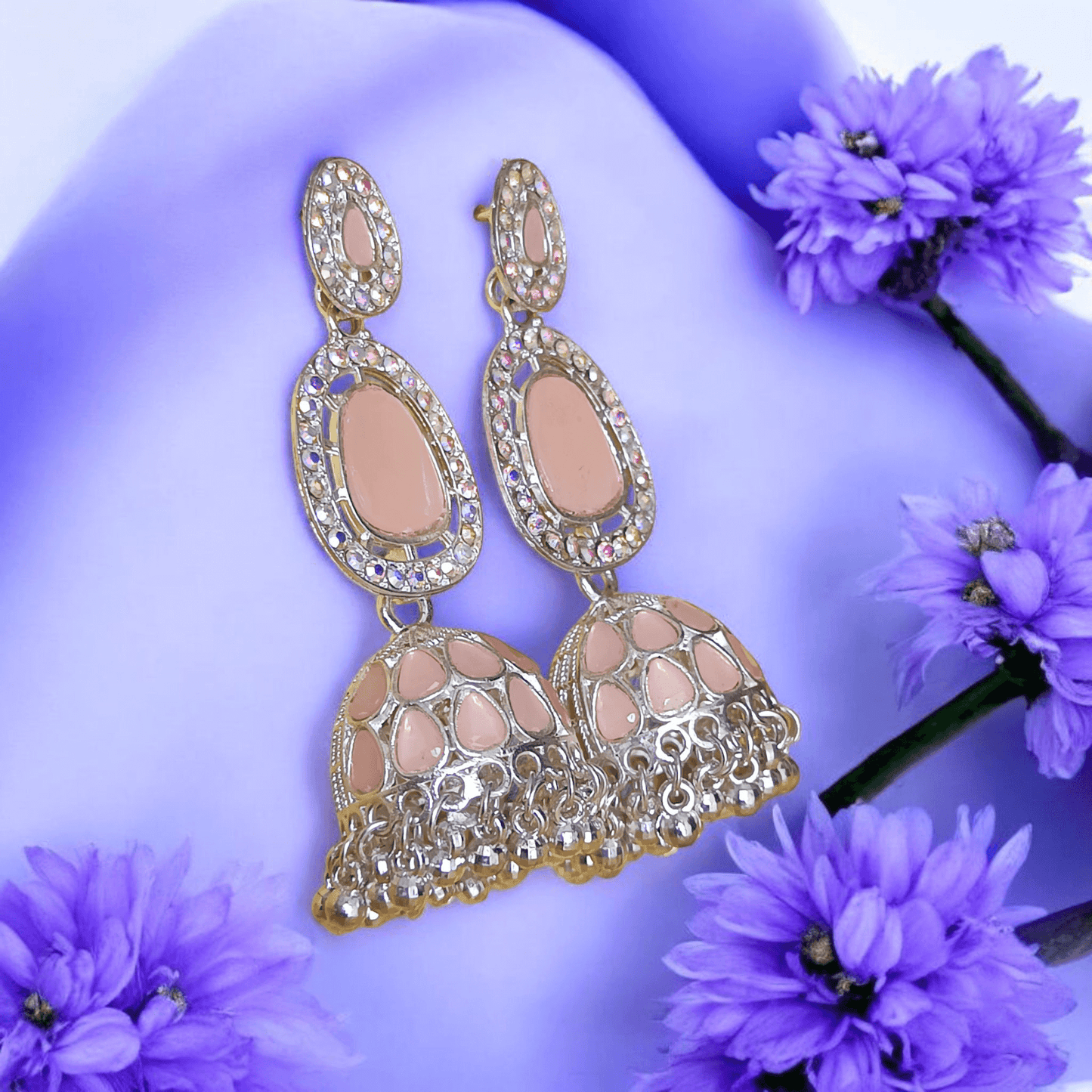 Selenesima peach oxidized jhumka earrings with embellishments against lavender flowers background
