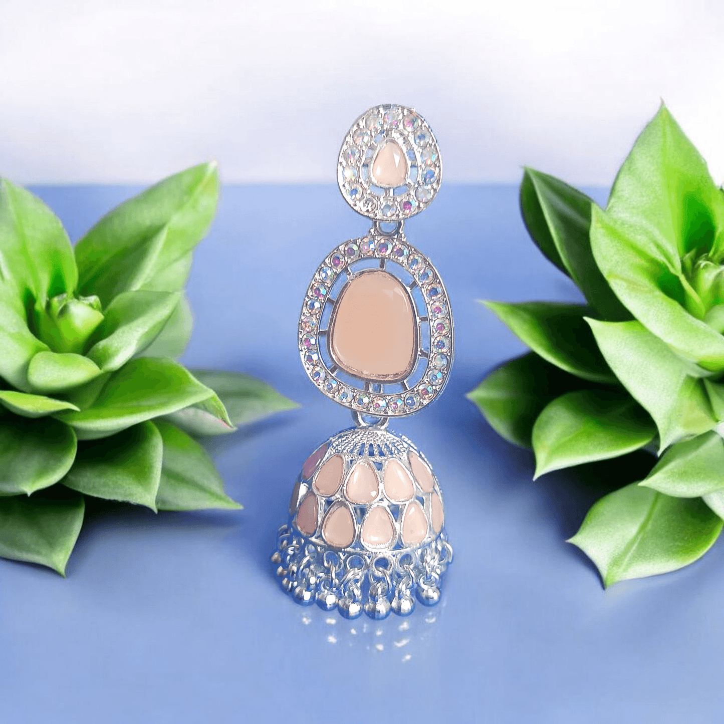 Selenesima peach oxidized jhumka earrings with embellishments against flowers background