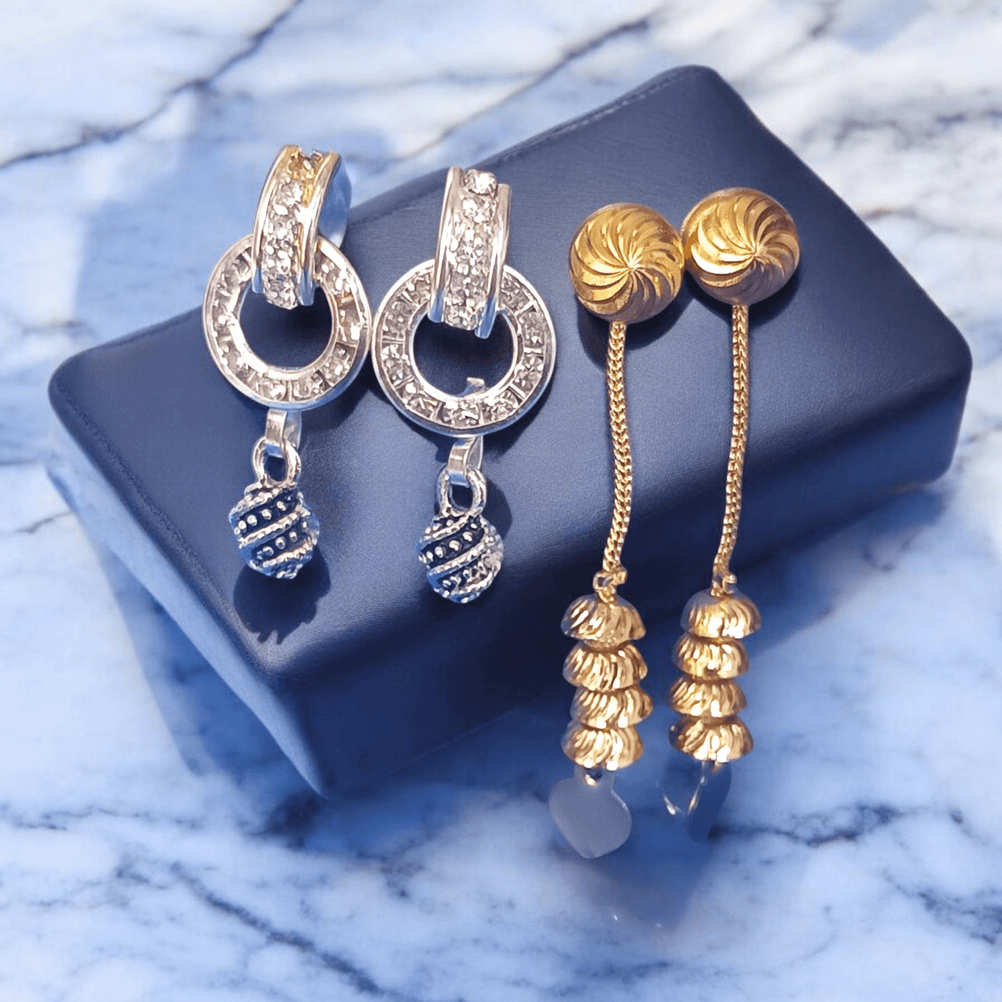 Antique gold long chain dangle earrings with stacked dome beads on a marble background"