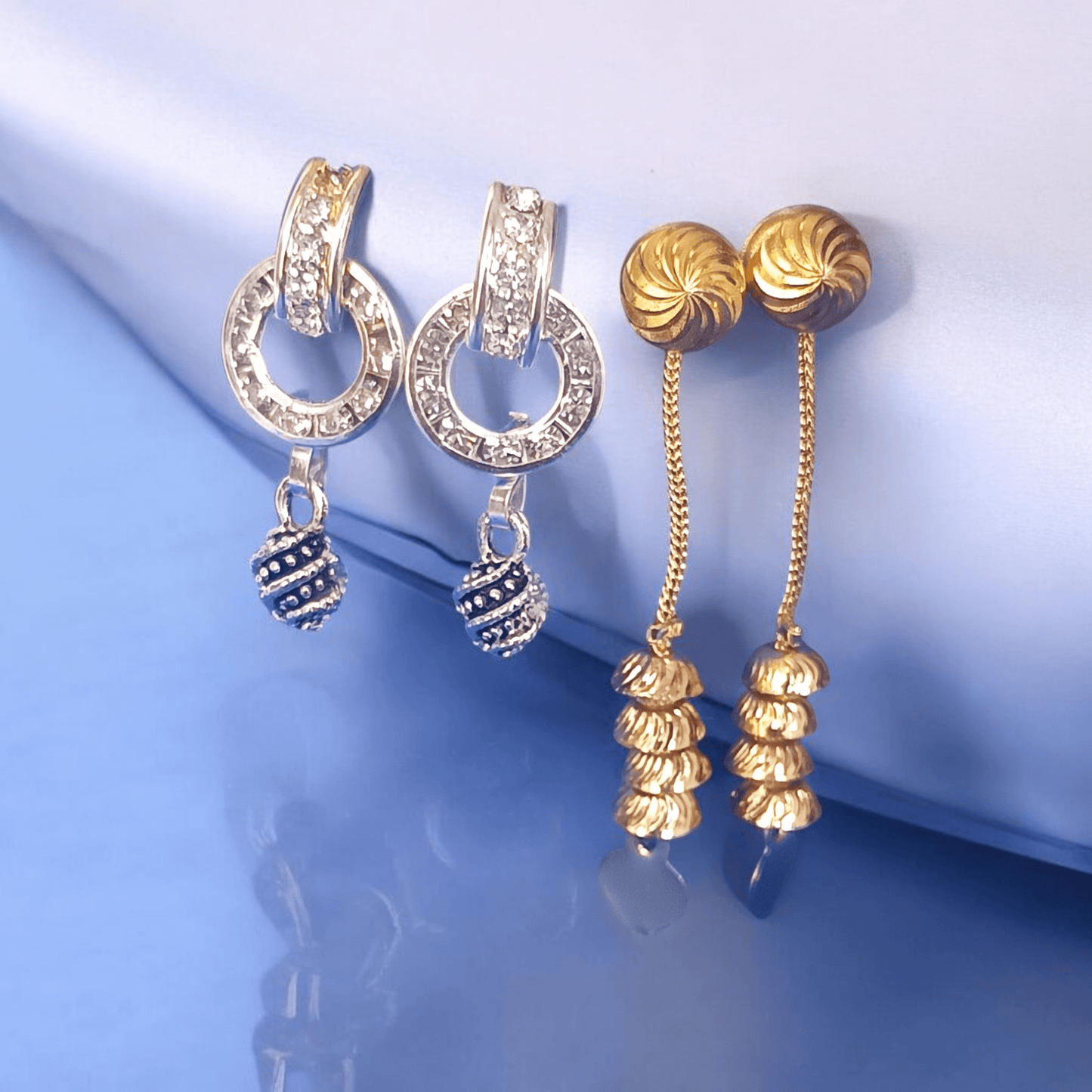 Antique gold long chain dangle earrings with stacked dome beads on a fabric background"