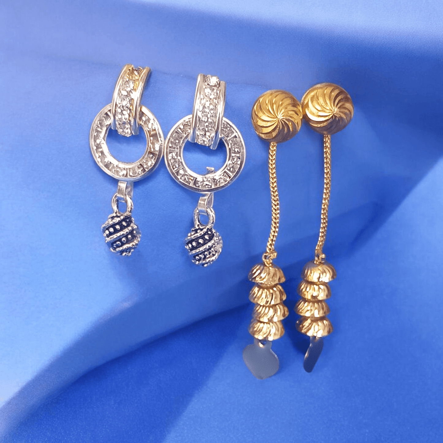 Antique gold long chain dangle earrings with stacked dome beads on a fabric background"