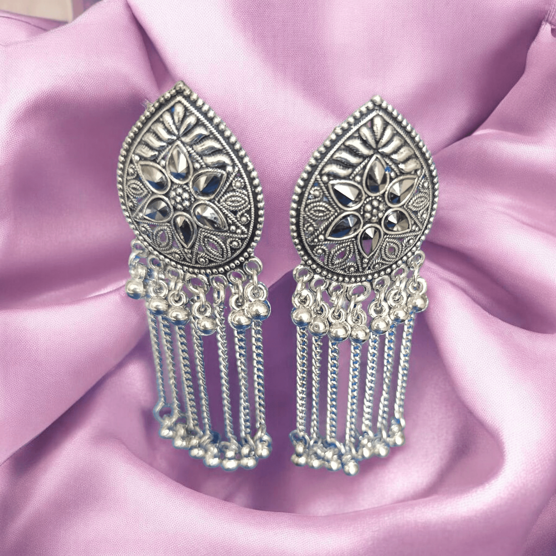 "Oxidized silver floral earrings with chain dangles on fabric background 