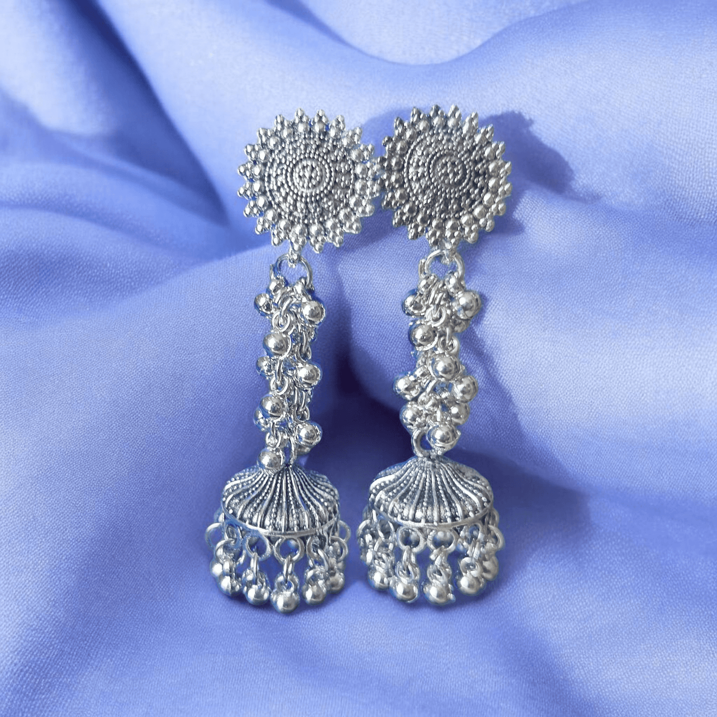 Close-up of oxidized silver earrings highlighting intricate carvings and chainwork