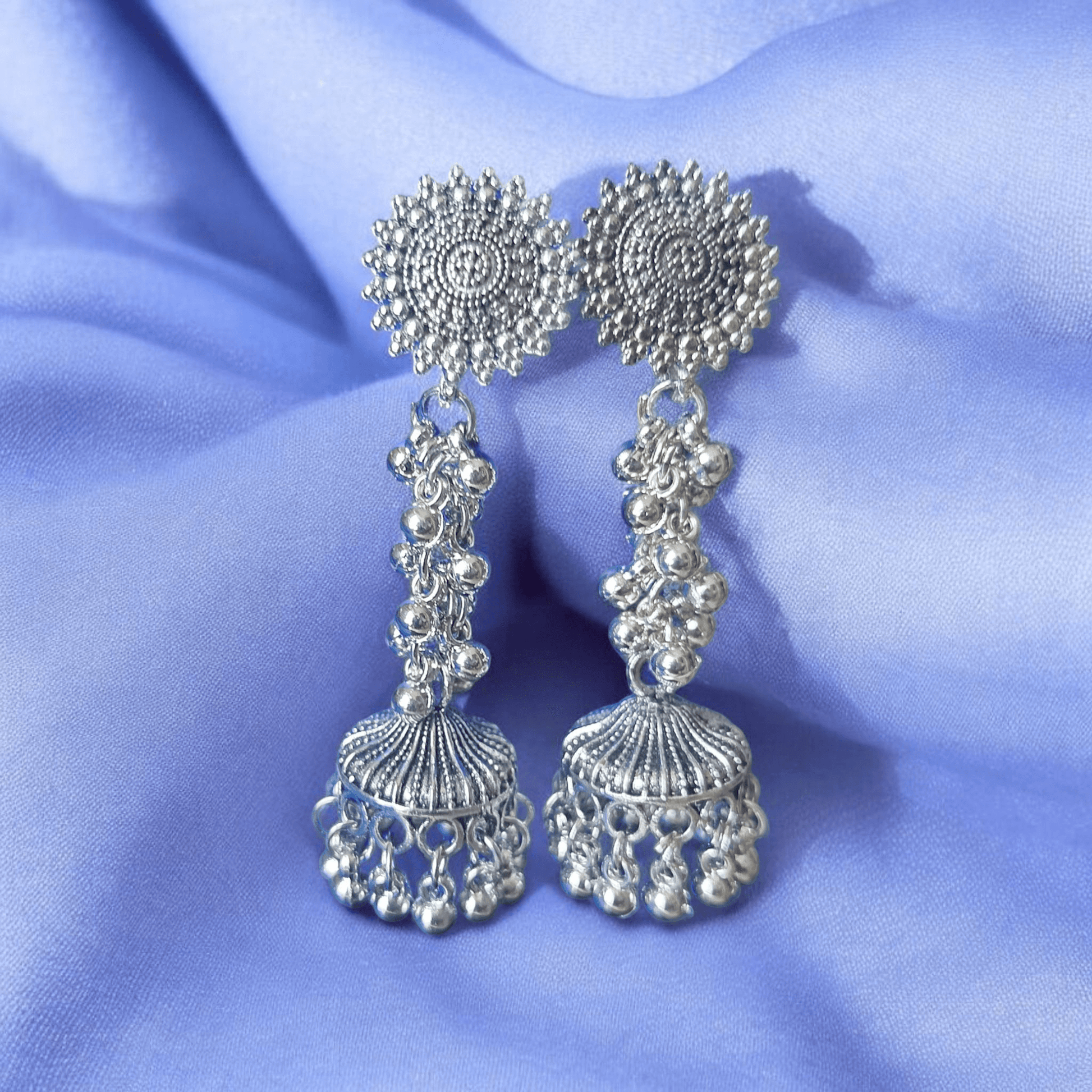 Close-up of oxidized silver earrings highlighting intricate carvings and chainwork