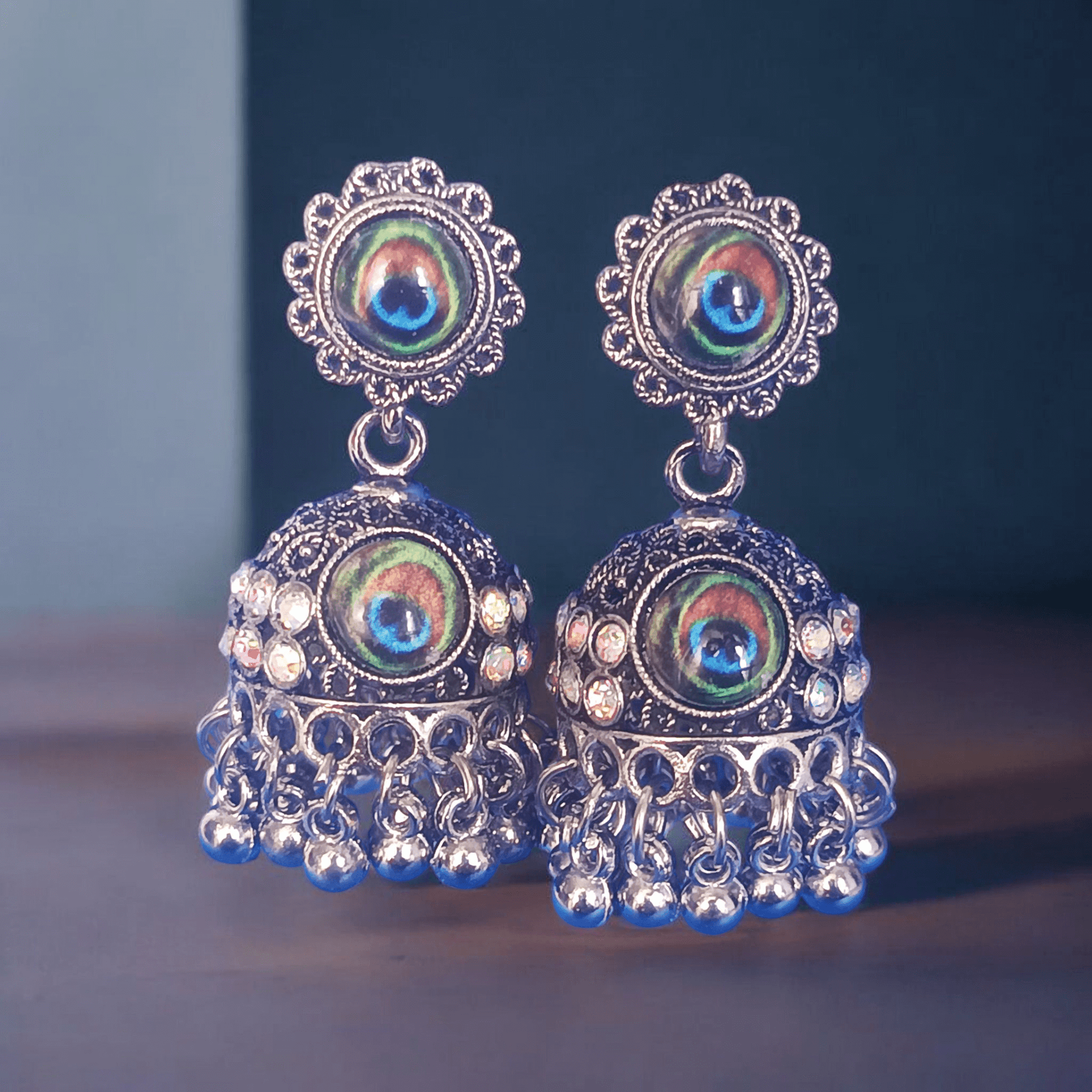Peacock design oxidized silver jhumka earrings with rhinestones and minimalist background