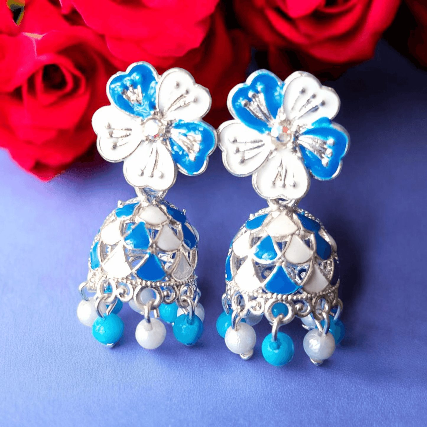 Selenesima blue floral oxidized jhumka earrings with pearls against red roses background