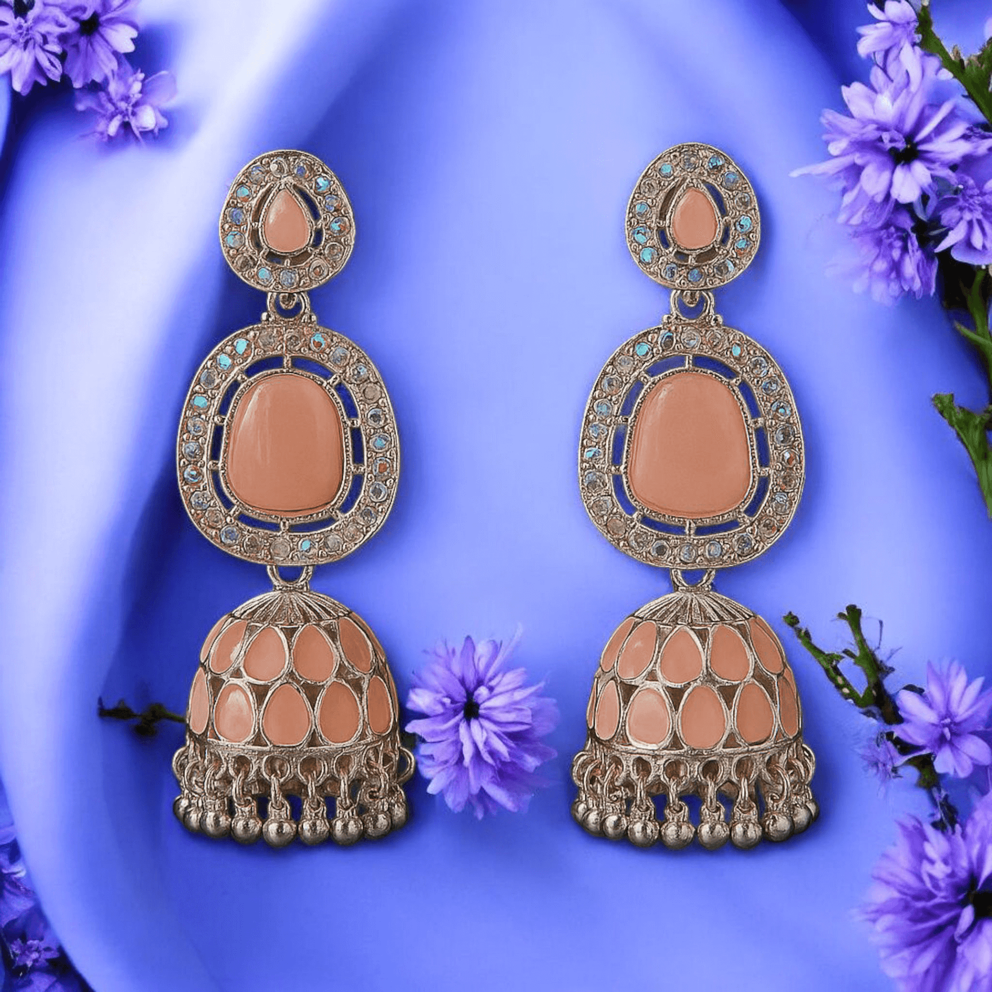 Selenesima peach oxidized jhumka earrings with embellishments against lavender flowers background