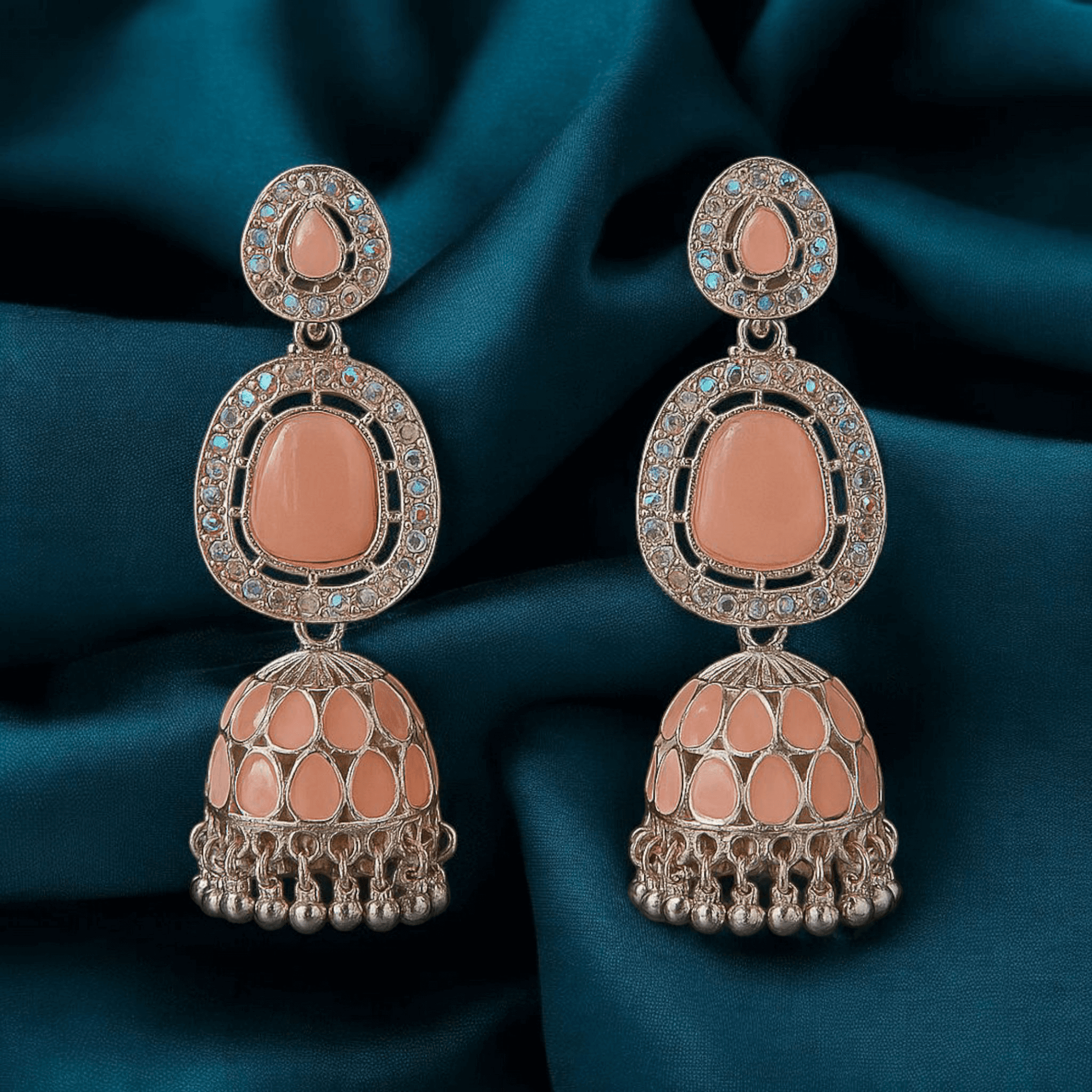 Selenesima peach oxidized jhumka earrings with embellishments against fabric background