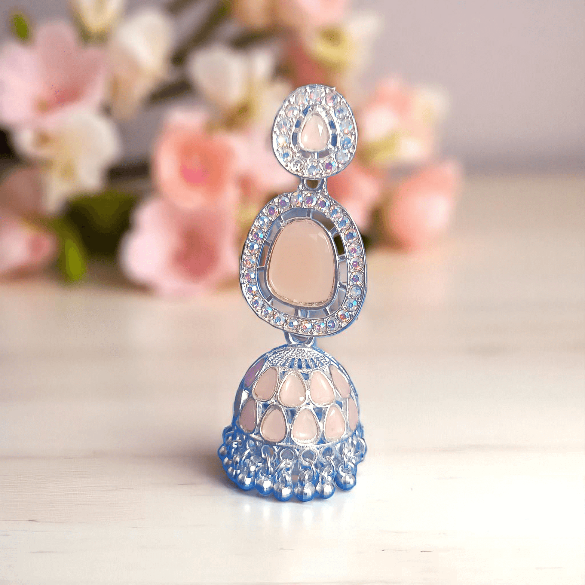 Selenesima peach oxidized jhumka earrings with embellishments against 
 flowers background