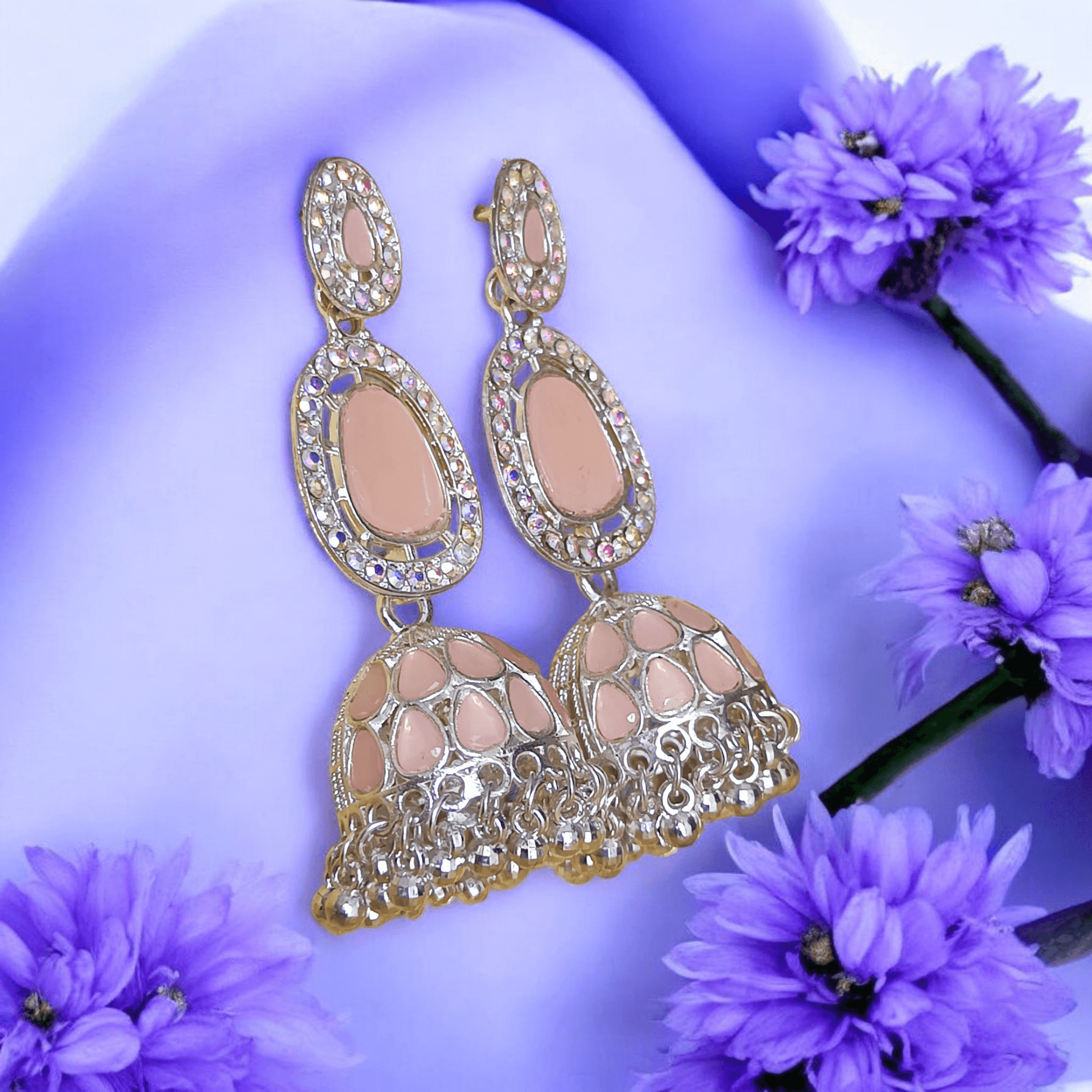 Selenesima peach oxidized jhumka earrings with embellishments against lavender flowers background