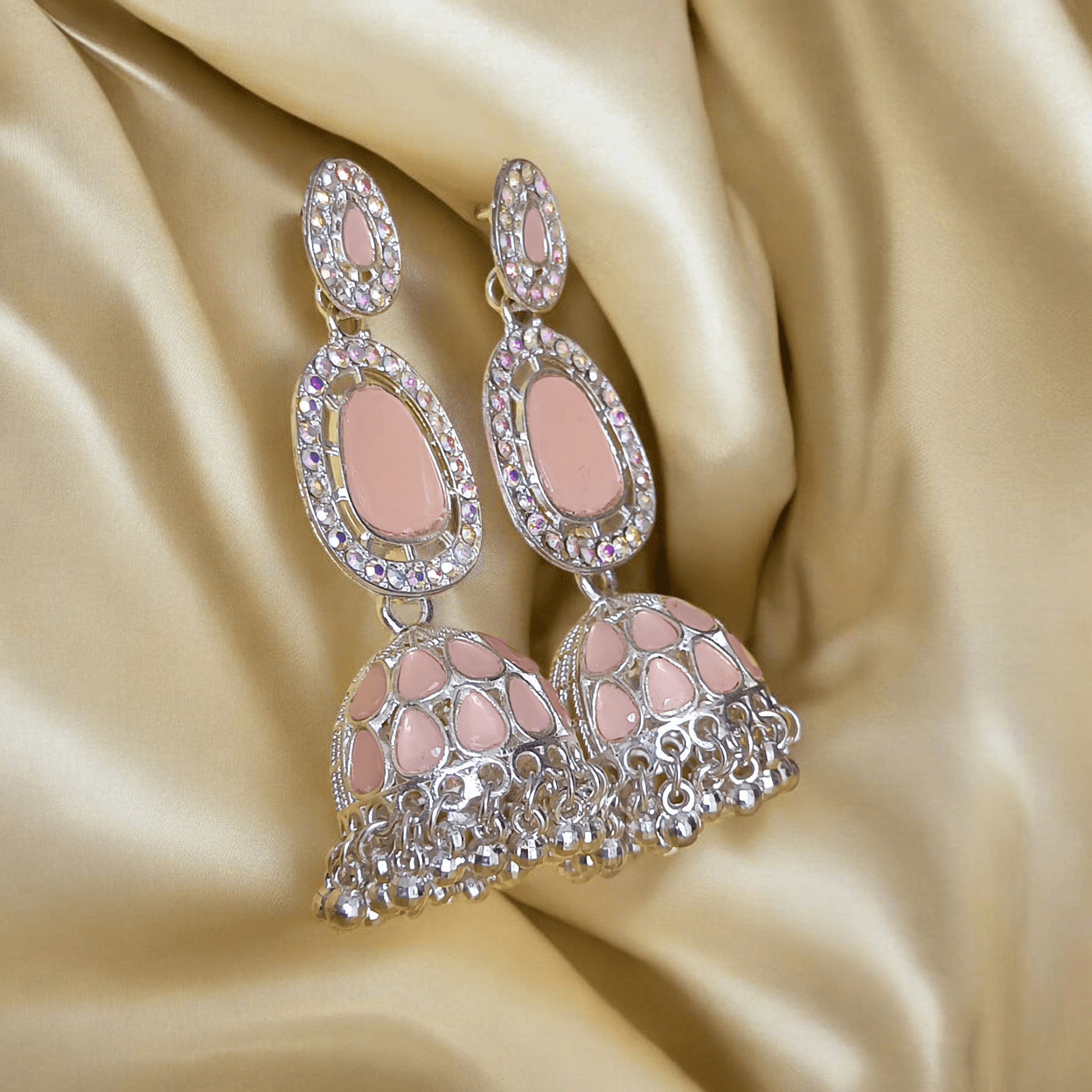 Selenesima peach oxidized jhumka earrings with embellishments against fabric background