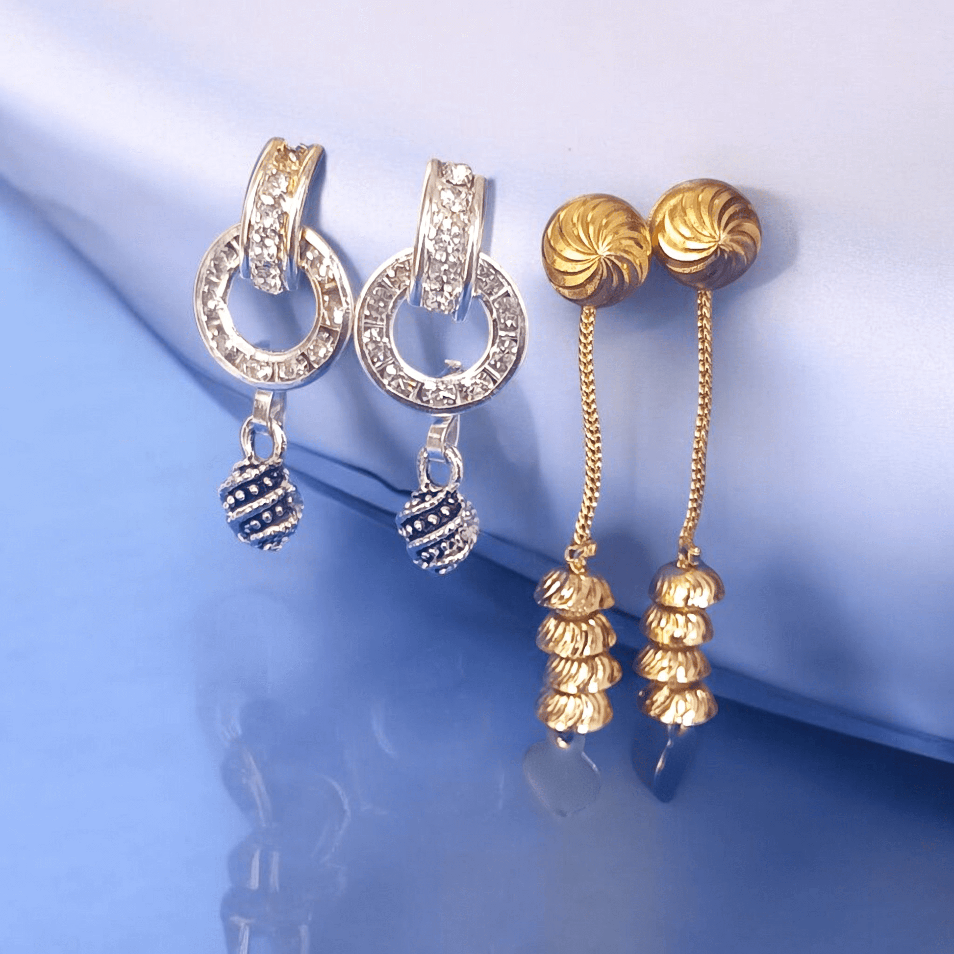 Antique gold long chain dangle earrings with stacked dome beads on a fabric background"
